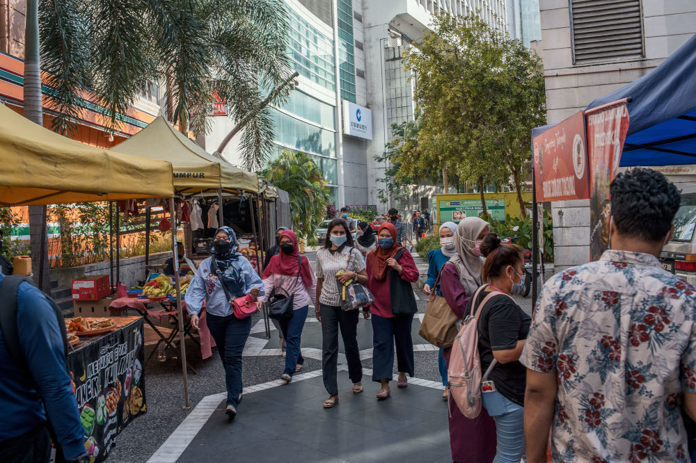 2022 年 3 月 3 日，人们在吉隆坡的 Jalan Tun Perak 散步时戴着防护口罩。 — 照片作者 Shafwan Zaidon