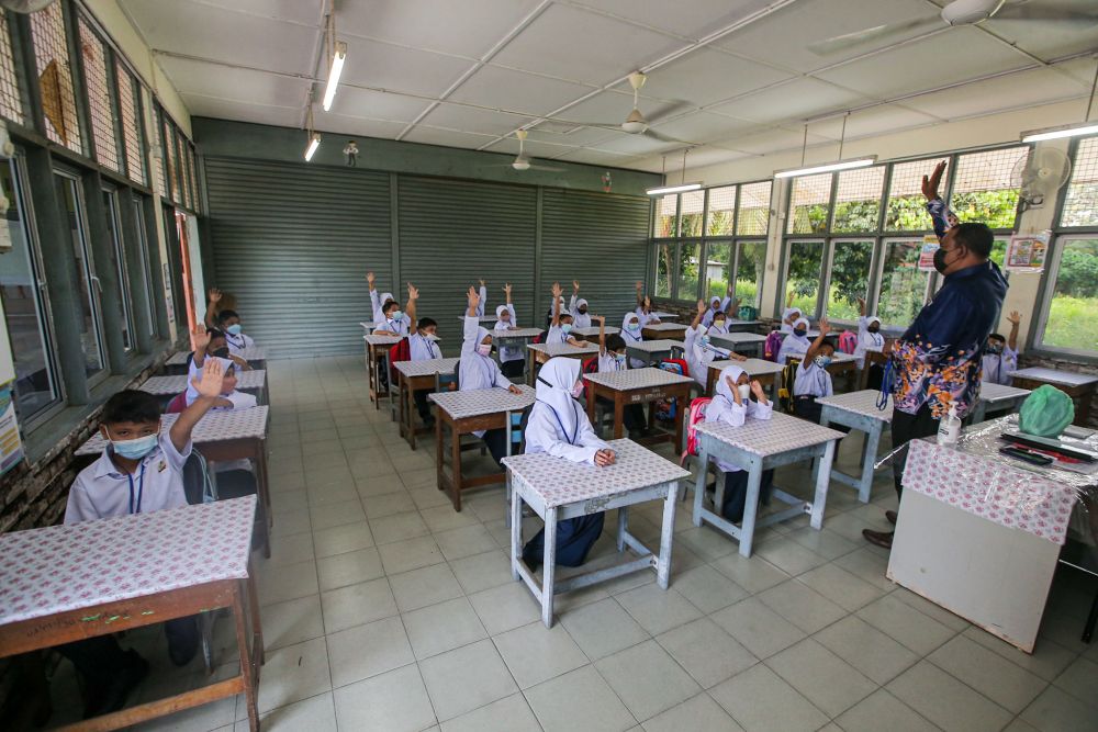 Siswa sekolah dasar kembali bersekolah di Sekolah Kebangsaan Syed Idrus Chemor di Perak 21 Maret 2022. — Gambar oleh Farhan Najib