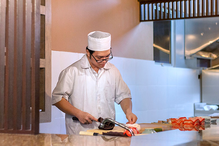 The sushi chef slicing fish for sashimi