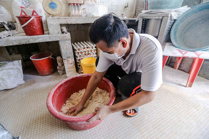 The dough for the noodles is shaken and loosened up before it is placed in the machine to flatten.