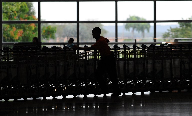 A porter is silhouetted as he pushes luggage trollies at Kuala Lumpur International Airport  in Sepang on August 19, 2010. u00e2u20acu201c AFP pic