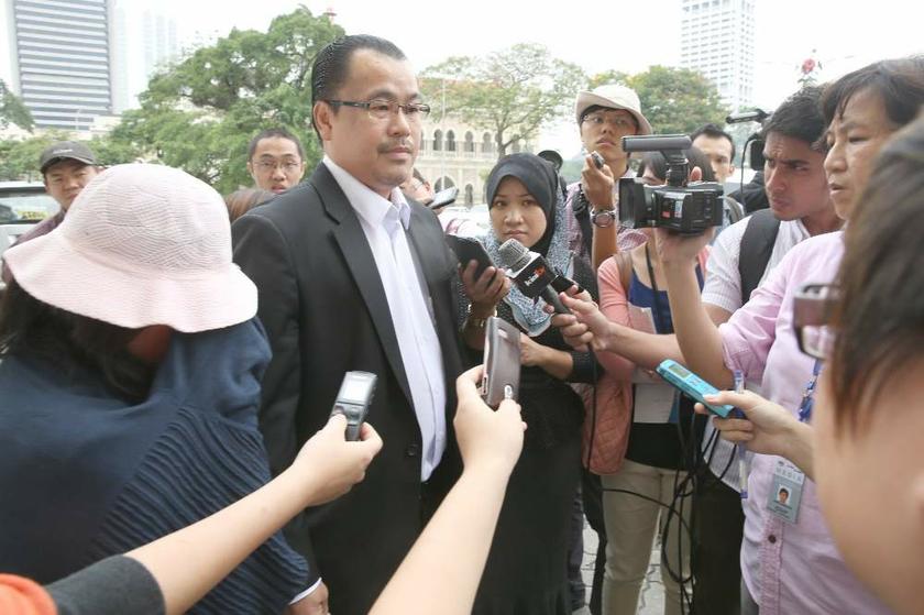 Lawyer Chong Joo Tian speaks to reporters while his client, the mother of sex blogger Alvin Tan, with cap covering her face, listens quietly, in Kuala Lumpur on August 5, 2013. u00e2u20acu201d Picture by Saw Siow Feng