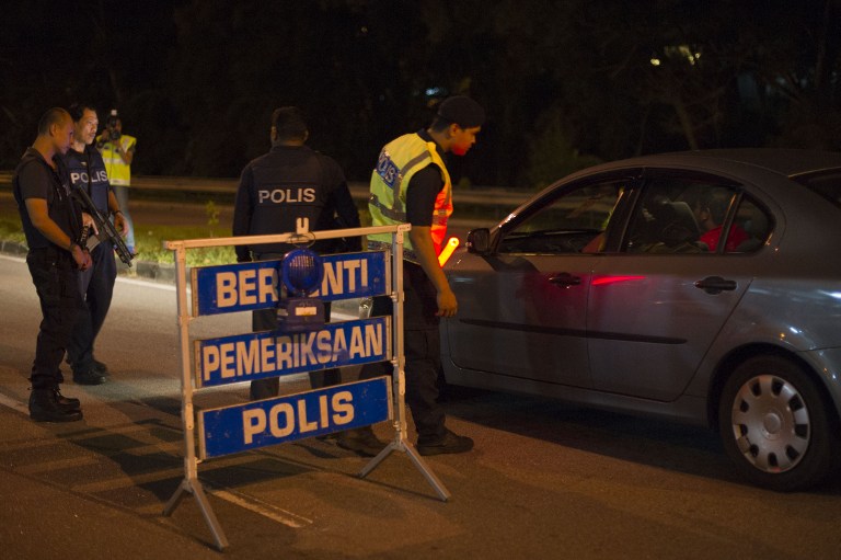 This picture taken in the early hours of August 21, 2013 shows Malaysian policemen checking a vehicle at a roadblock during an operation called 'Op Cantas Khas' in Kuala Lumpur. u00e2u20acu201c AFP pic