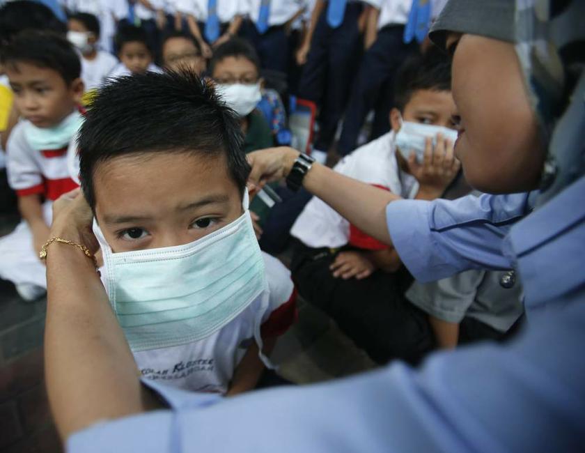 A teacher helps her student put on a face mask due to the haze at a school in Putrajaya on June 26, 2013. u00e2u20acu201d Reuters pic