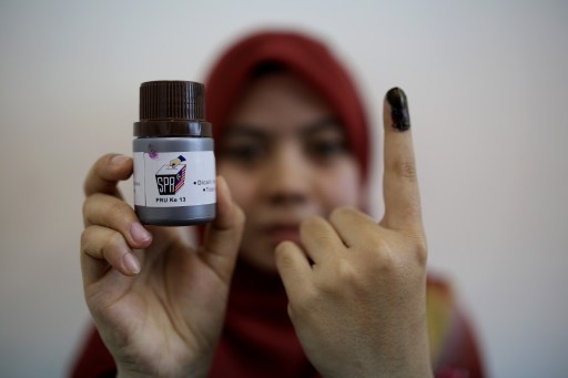 An Election Commission officer, Haziyatul Amirah, shows an indelible ink bottle during a demonstration at the Election Commission offices in Putrajaya on May 2, 2013. u00e2u20acu201d AFP pic