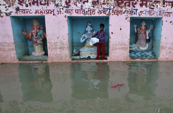 A boy stands next to an idol of Hindu Lord Shiva at a temple submerged in the waters of the river Ganges in the northern Indian city of Allahabad September 2, 2013. u00e2u20acu201d Reuters pic