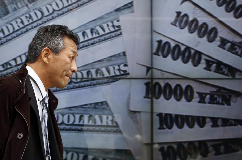 A pedestrian walks past electronic boards showing the picture of Japanese 10000 yen banknotes and 100 US dollar banknotes outside a brokerage in Tokyo January 9, 2014. u00e2u20acu201d Reuters pic