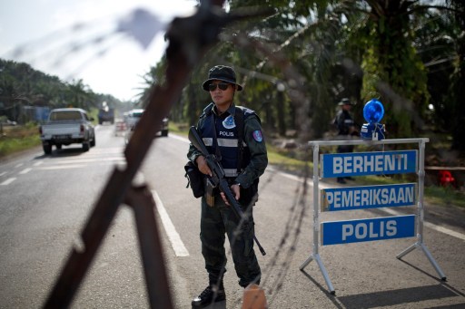 An armed Malaysian policeman mans a security checkpoint in Lahad Datu on March 6, 2013. — AFP pic