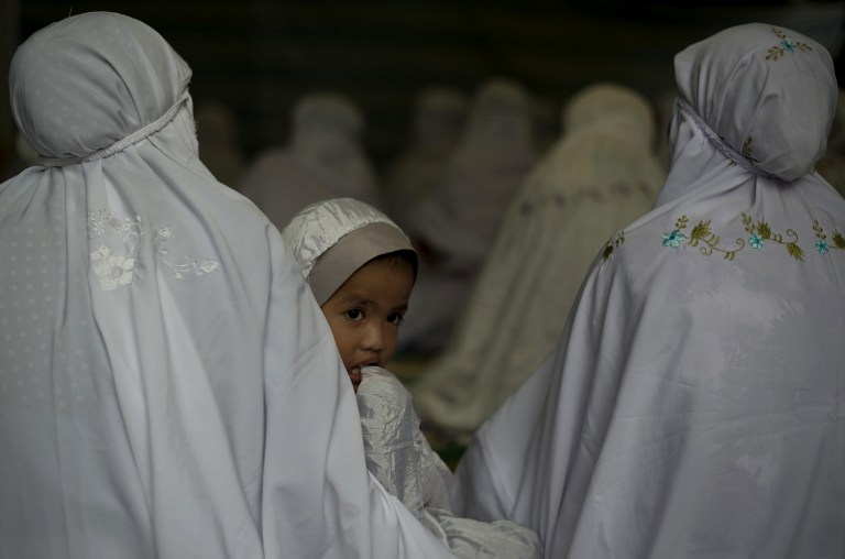 A girl looks on before Eid al-Adha prayers in Kuala Lumpur on October 15, 2013. Eid al-Adha is celebrated throughout the Muslim world in remembrance of Abraham's readiness to sacrifice his son to God with cows and goats traditionally slaughtered on this h
