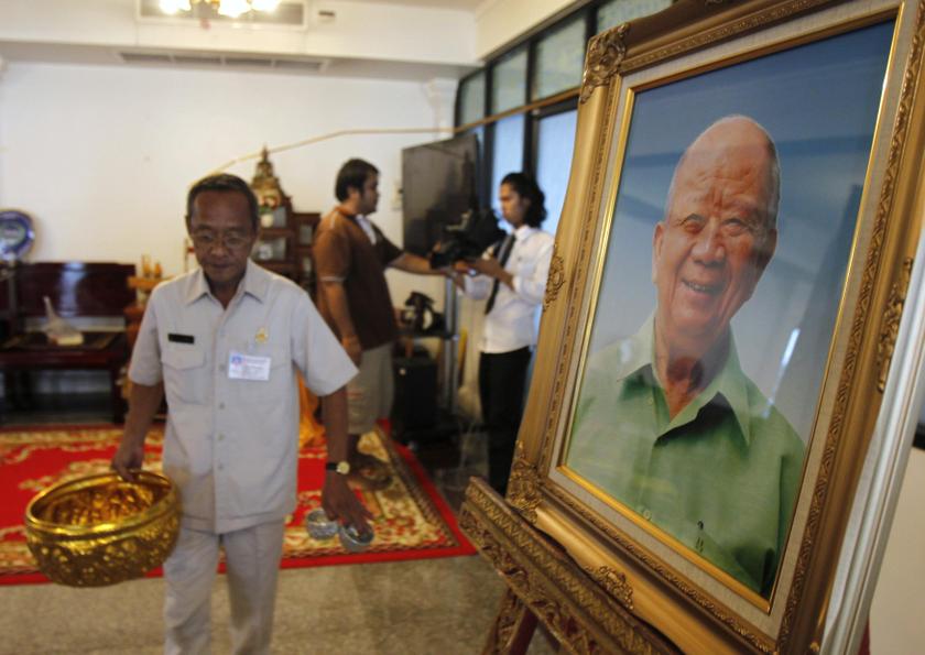 An undertaker carries a bowl near a portrait of former Malayan Communist Party leader Chin Peng during his funeral at a temple in Bangkok September 20, 2013. u00e2u20acu201d Reuters pic