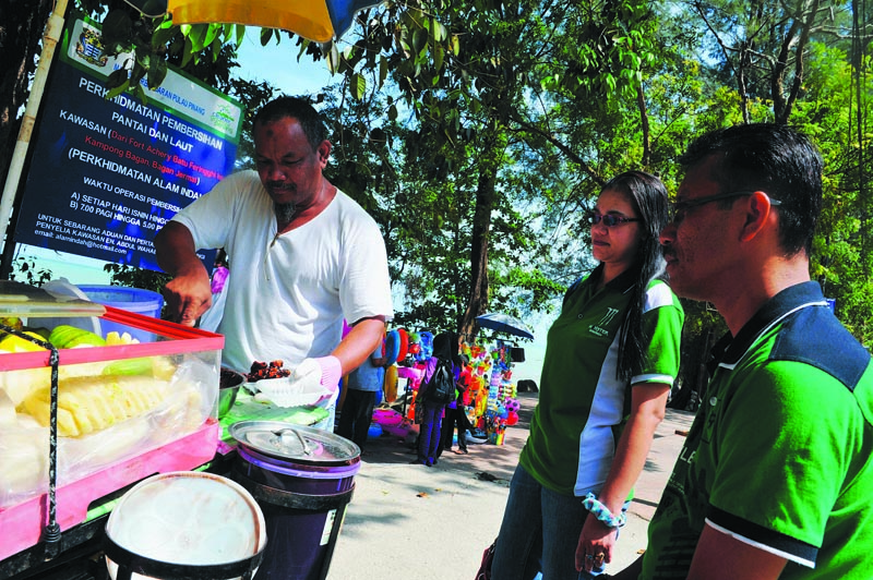 Annas prepares another plate of 'rojak' for Osman Tukimin and Nor Aini Ahmad from Kuala Lumpur as he recalls that fateful day nine years ago when a tsunami swept into Miami Beach u00e2u20acu201du00c2u00a0Picture by Sayuti Zainudin